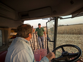 Grower greeting Pioneer rep from harvester cab